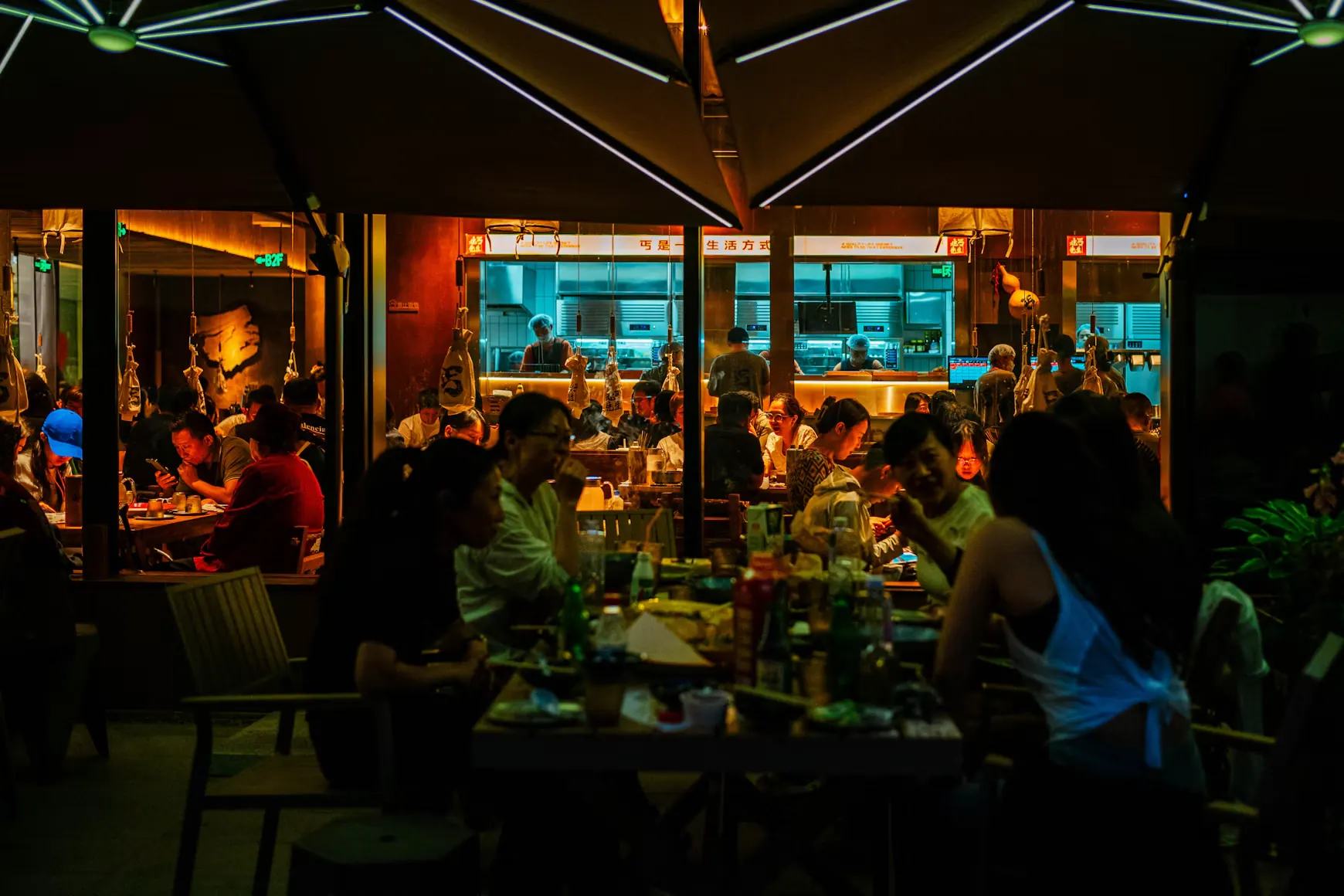 Des clients attablés en terrasse d'un restaurant, le soir